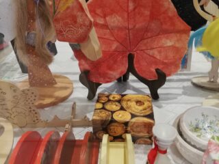 Stół z drewnianymi oraz ceramicznymi ozdobami m.in. miseczki, figurki, pudełka oraz ceramika w kształcie liścia.