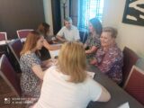Warsztaty sieciujące dla Podlaskich Sieci Współpracy o zarządzaniu zasobami ludzkimi. Sześć osób siedzi przy stole, jedna z kobiet notuje na dużej kartce.
