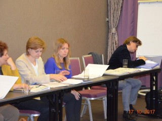 Cztery kobiety siedzą przy długim stole i przeglądają dokumenty.