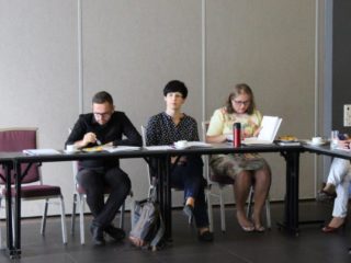 Kilka osób siedzi przy stole z dokumentami.