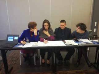 Cztery osoby siedzą przy jednym stole i pracują nad projektem.