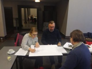 Trzy osoby siedzą przy jednym stole i pracują nad projektem.