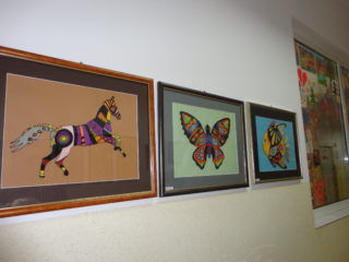 Trzy obrazy zrobione z nici które przedstawiają konia, motyla oraz rybę. Obrazy wiszą na ścianie.