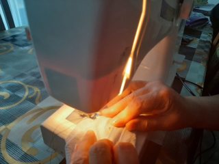 Osoba szyje maseczki na maszynie do szycia.