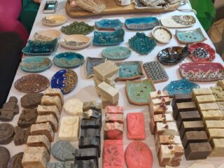 Stół z nietypowymi zdobionymi talerzykami, słoikami z mięsem i bloczkami pokrojonymi na kawałki.