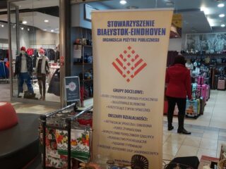 Baner Stowarzyszenia Białystok-Eindhoven Organizacji pożytku publicznego. Obok stoi stoisko z ozdobami.